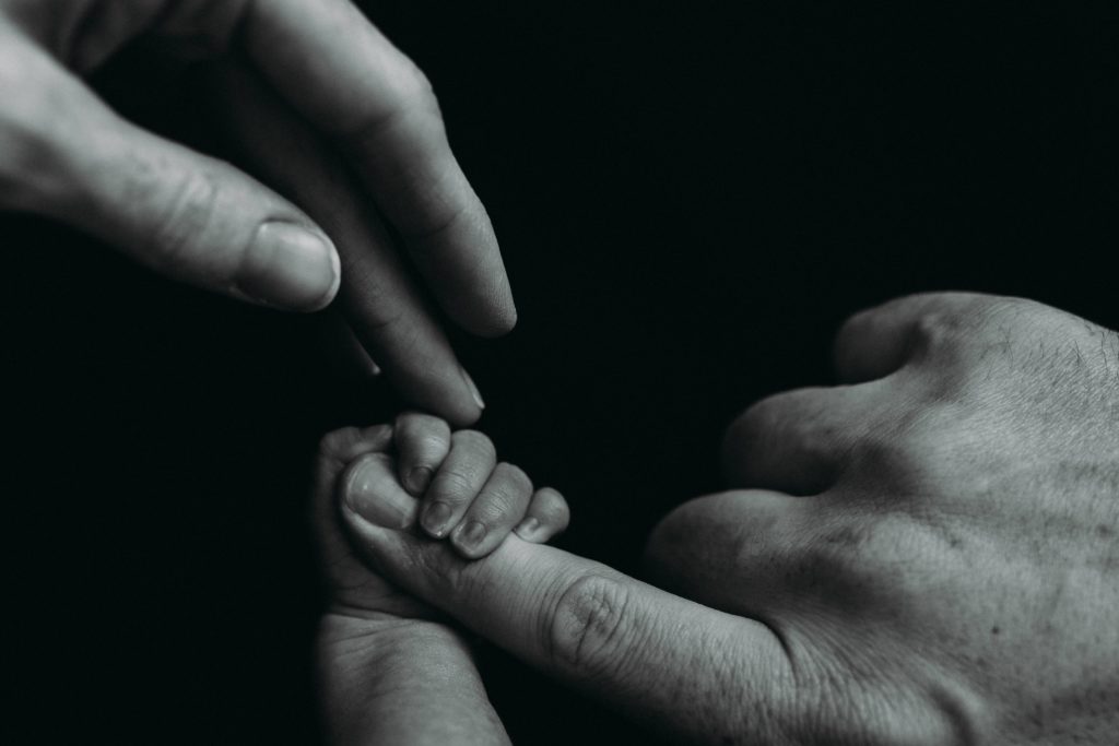 Newborn baby holding dad's hand at studio in Janesville, Wisconsin