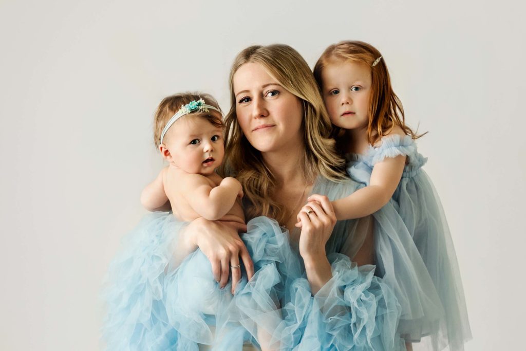 Mom and daughters in blue in studio at mommy and me session