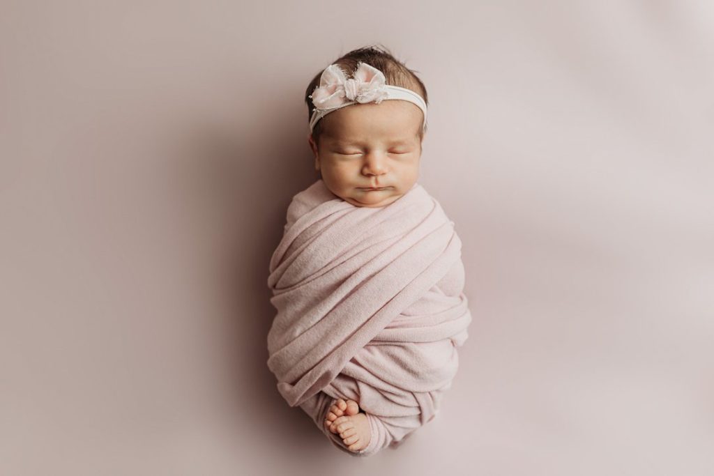 Newborn baby in pink with bow by Olivia Acton Photography in Janesville, WI