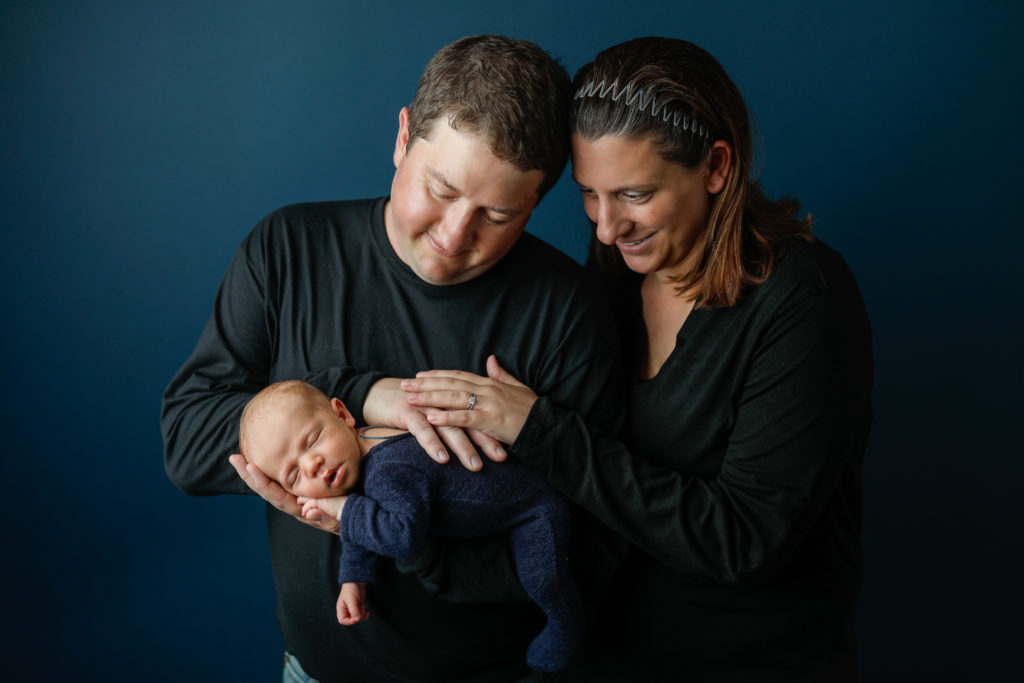 baby boy with mom and dad in studio with blue background by Olivia Acton Photography