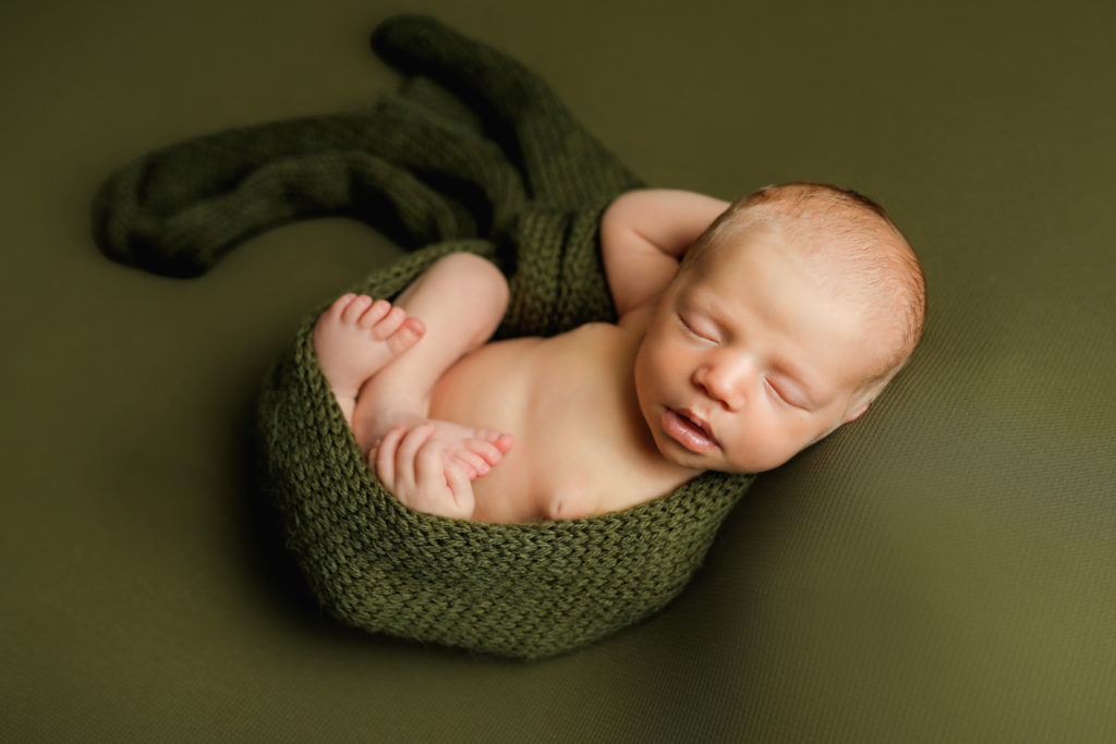 Newborn in posed in green by Olivia Acton Photography in Janesville, WI