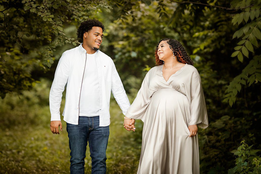 Couple at maternity session holding hands outdoors in Janesville, WI by Olivia Acton