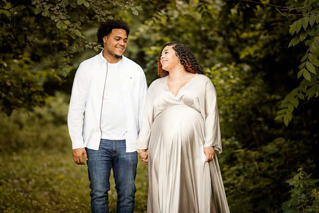 Couple at maternity session holding hands outdoors in Janesville, WI