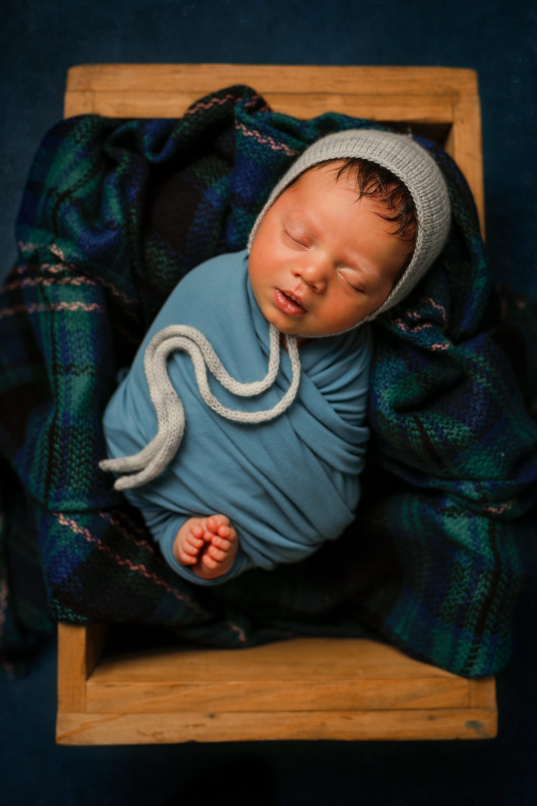 Newborn baby boy in blue with bonnet in props in Janesville, WI
