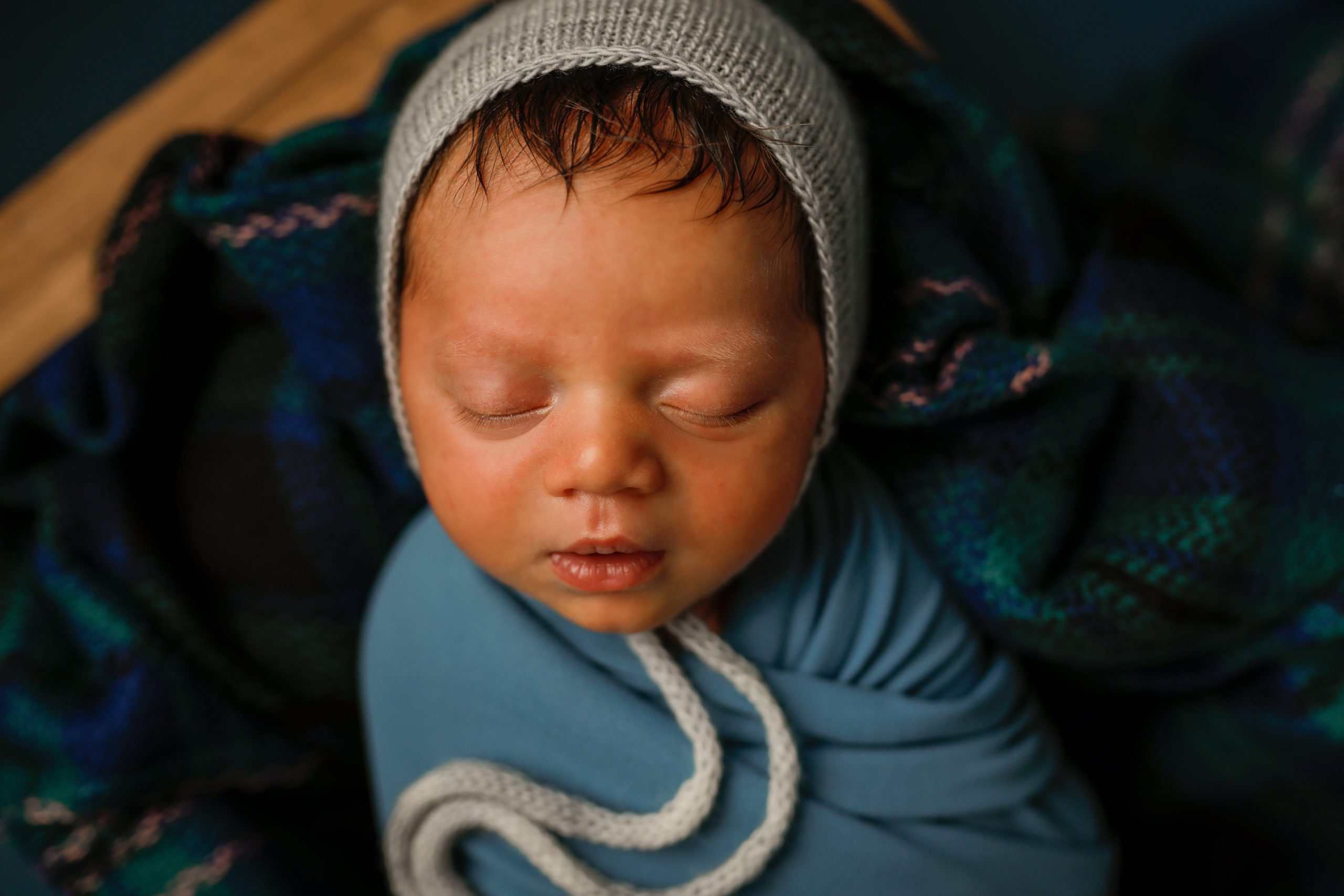 Newborn baby boy in blue with bonnet in props in Janesville, WI